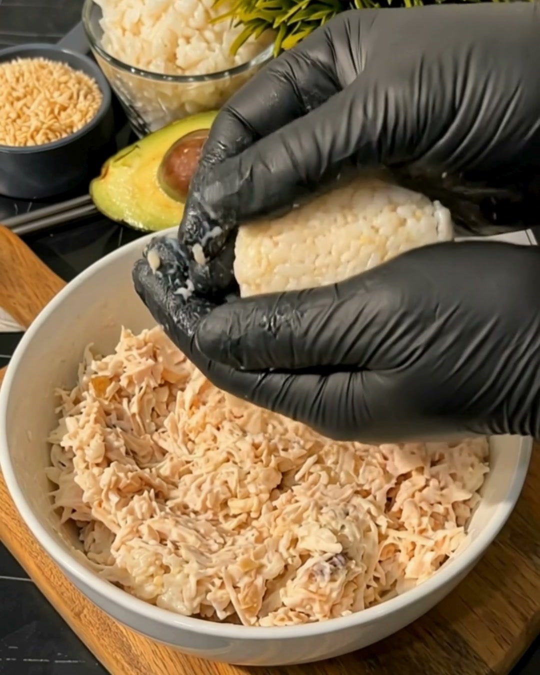 Manos formando una bolita de arroz rellena con pollo y queso crema Comalich