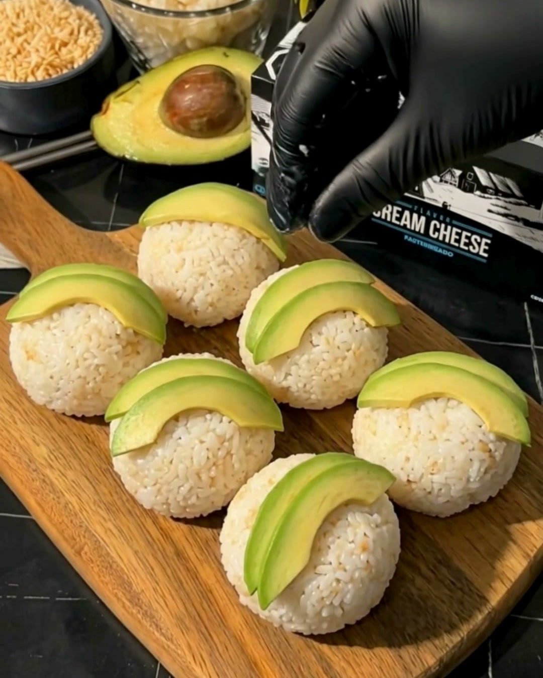 Bolitas de arroz decoradas con laminas de palta y sesamo junto al queso crema Comalich