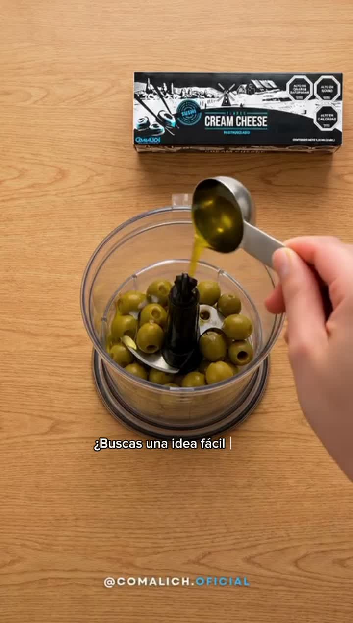 Aceitunas verdes con aceite de oliva en procesador — queso crema Comalich al fondo